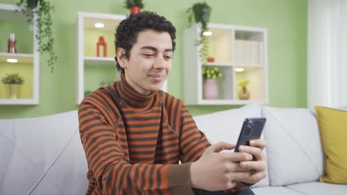 Young Adult Using Smartphone Relaxing on Sofa