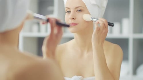 Woman Applies Makeup with a Brush in Bathroom