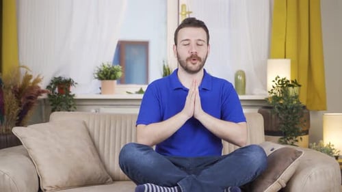 Man Meditating Calmly on Couch at Home