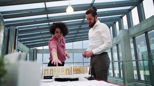 Young architects discussing a house model project in a modern office