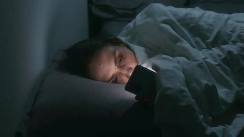 Woman Browsing Phone in Bed at Night