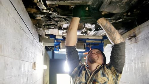 Mechanic Repairing Car Undercarriage in Auto Repair Shop