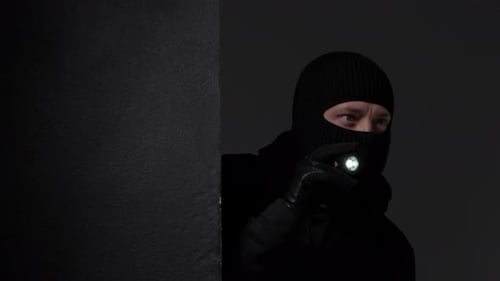 Figura mascarada com lanterna espreitando ao redor da parede