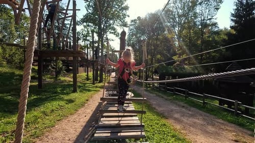 Happy Little Girl Playing in Tarzan Attraction on Playground in Amusement Park. Little Girls Enjoy P
