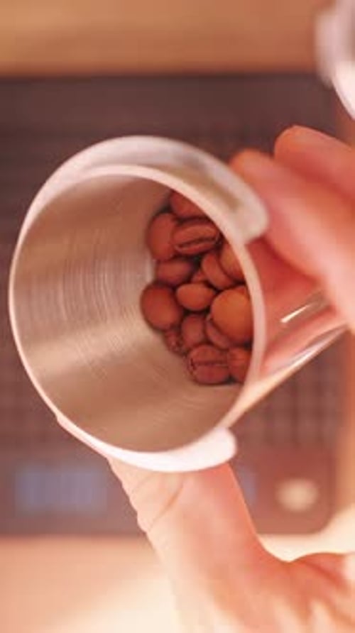 Vertical video. Man holding measured Coffee Bean dose in metal cup after precise weighing, Top View