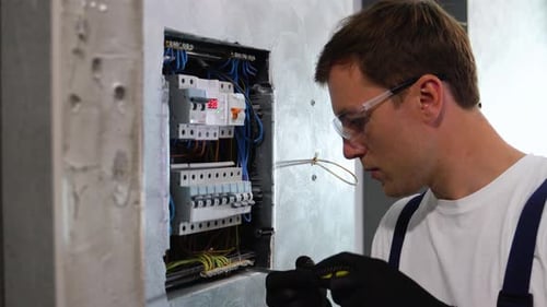 Electrician Working with Wiring and Electrical Panel