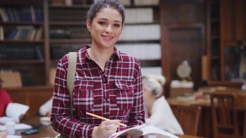 Happy university student smiling proudly in college library with classmates