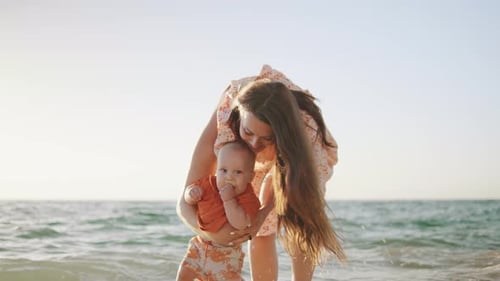 Mother and Baby Enjoy a Sunny Day at the Beach Playing in the Waves and Sharing Joyful Moments