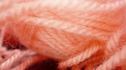 A ball of pink woolen threads, on black glass.. Dolly slider extreme close-up. Laowa Probe