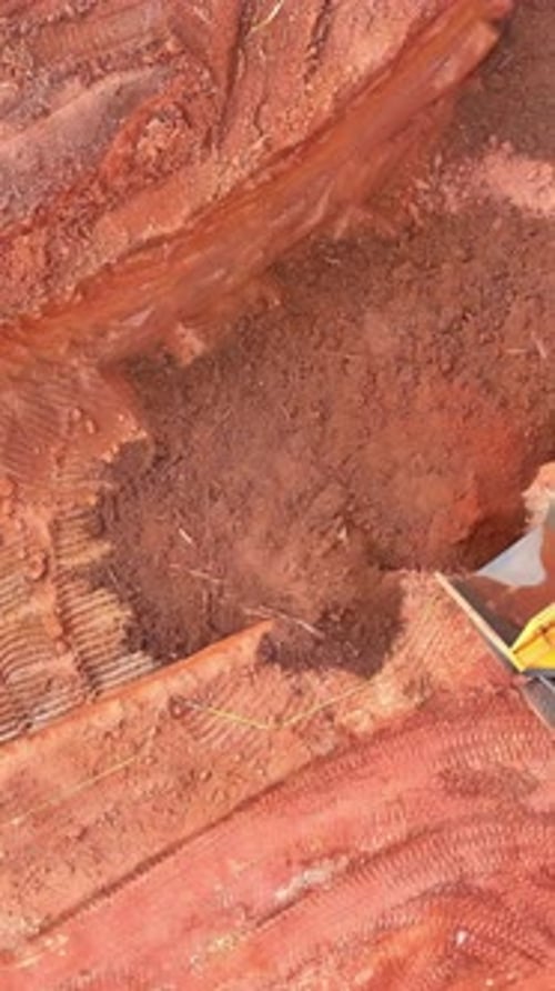 Excavation Work Underway at a Construction Site with Heavy Machinery in Red Soil