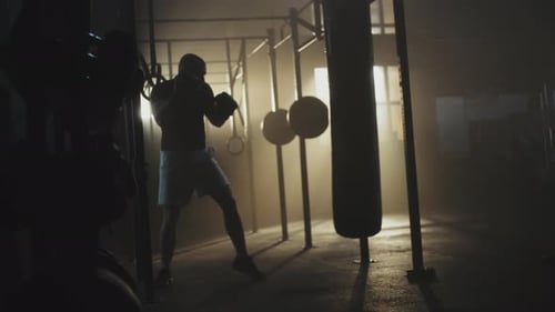 Man Punches Heavy Bag During Night Boxing Training