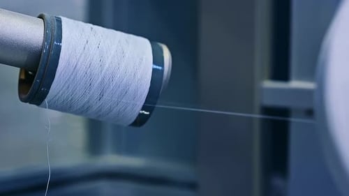 Nylon white thread being unwind from a thick reel.