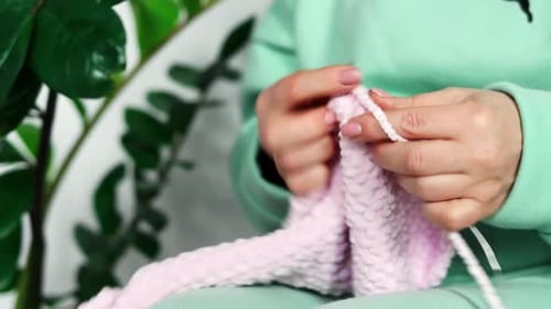 Woman's hands with yarn are knitting handmade wool clothes close-up. The concept of needlework