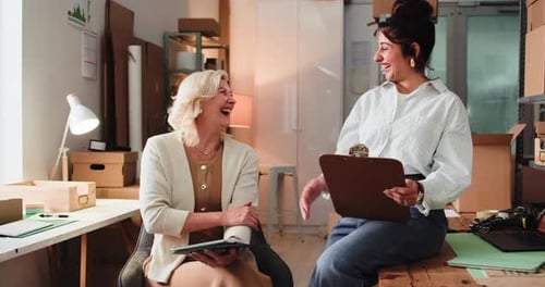 Two Smiling Women Giving High Five in Office
