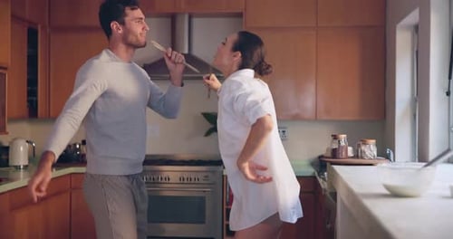 Playful Couple Dancing and Singing in Kitchen