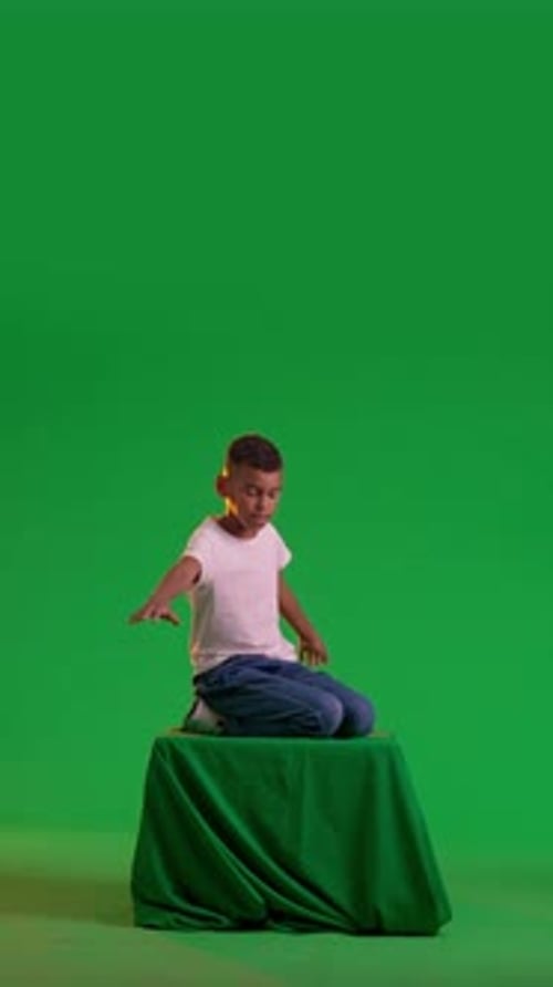 Playful Schoolboy Flying on a Green Box at a Green Screen