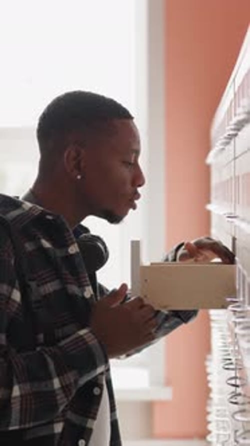 Man with Backpack Seeks for Library Ticket in Drawer