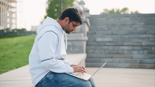 Young Adult Man Using Laptop in an Urban Setting