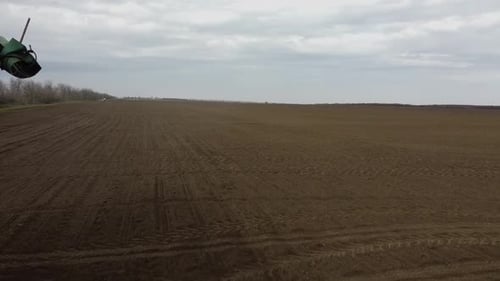 Blue tractor with yellow seeder working on the field in Ukraine OA