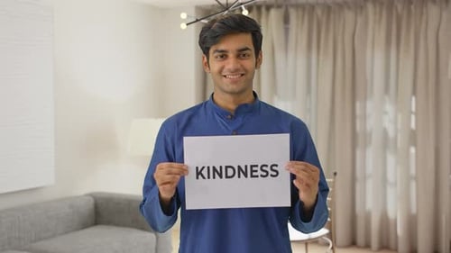 Young Adult Holding Kindness Sign Indoors Smiling