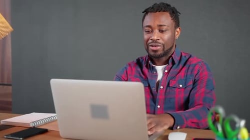 Joyful Black Man Chatting By Video Call in Laptop From His Home Office Smiling to Web Camera