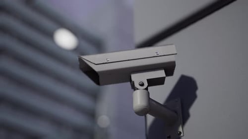 Outdoor CCTV Security Camera Mounted on Building Wall with Blurred City