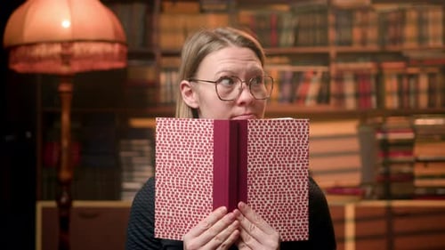 Young Woman Peeks From Behind Book in Cozy Library Emphasizing Reading She Playfully Flirts and
