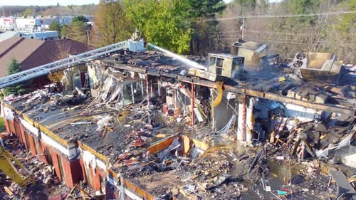 Un pompier fait exploser de l'eau dans un bâtiment incendié sur le point de s'effondrer