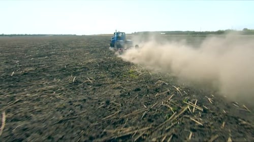 Luftaufnahme eines Traktors mit Eggensystem beim Pflügen von Boden auf bewirtschaftetem Ackerland bei der Bearbeitung des