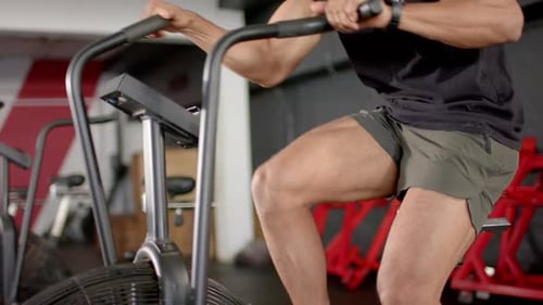 Exercising intensely, man using stationary bike for cardio workout in gym