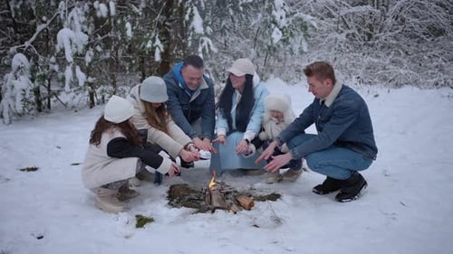 Happy Family Warming by Campfire in Snowy Forest