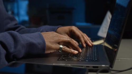Adult Typing on Laptop in Dark Blue Light