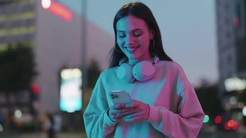 Young Woman Using Phone at Night in Neon Light
