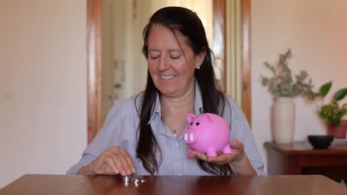 A Joyous Woman Depositing Money into a Piggy Bank - Static Shot