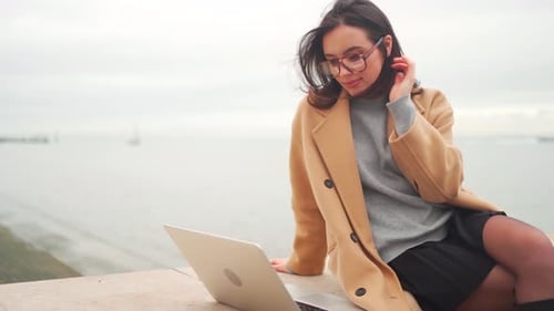 Young Woman Works on Laptop by the Water