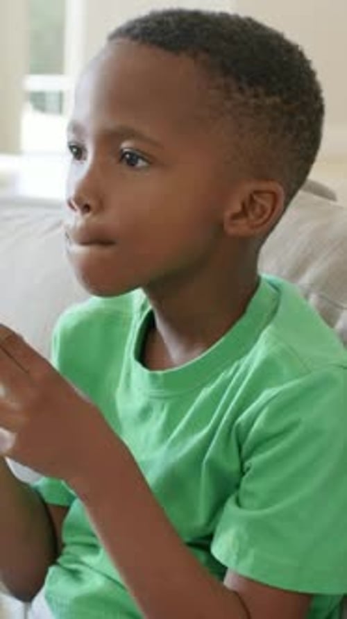 Vertikales Video: Spielender Junge mit grünem Tee auf der Couch zu Beginn des Spiels, Anpassung des weißen Controller-Griffs