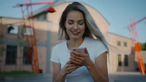 Attractive Woman Using Phone Outside Building On Sunny Day
