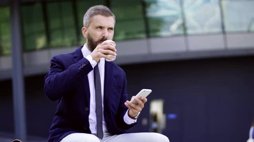 Mature hipster businessman relaxes with coffee and smartphone in London england