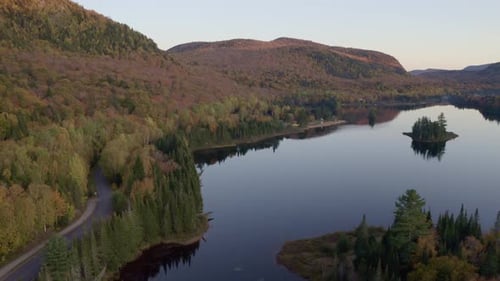 Descending Drone Shot of a Forested Lakeshore with a Scenic Island in Autumn