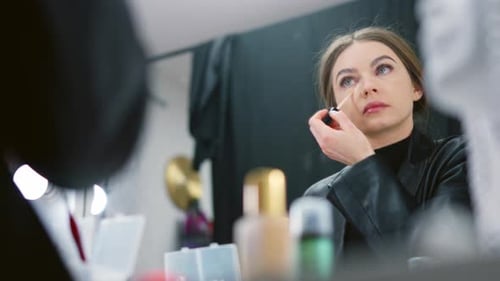 Woman Applies Makeup in Front of Vanity Mirror