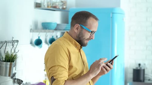 Man in kitchen using smartphone