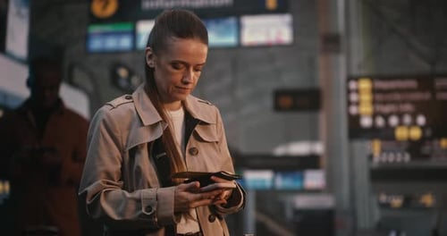 Woman Holds Passport and Phone at Airport Terminal