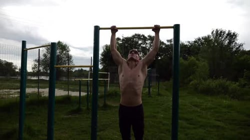 Muscular Athlete Doing Pull Ups on Horizontal Bar at Sports Ground Young Shirtless Sportsman