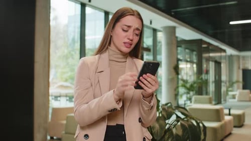 Young Businesswoman Using Smartphone Becomes Shocked Sudden Lottery Results in Office Hotel Lobby