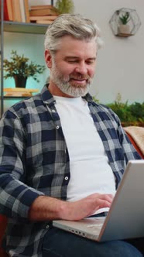 Man Uses Laptop While Sitting on Couch Indoors