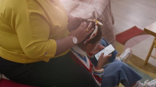 Adult Fixing Hair of Child Using Cell Phone