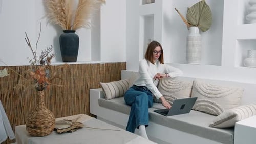 Woman Typing on Laptop in Bright Modern Room