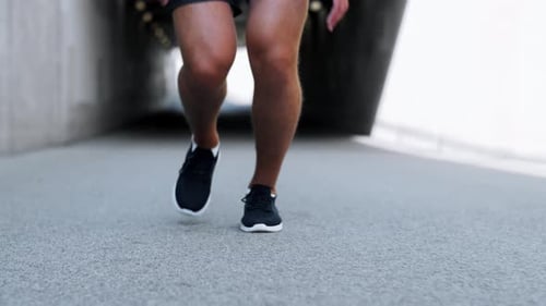 Young man running out of tunnel in city for fitness and healthy lifestyle