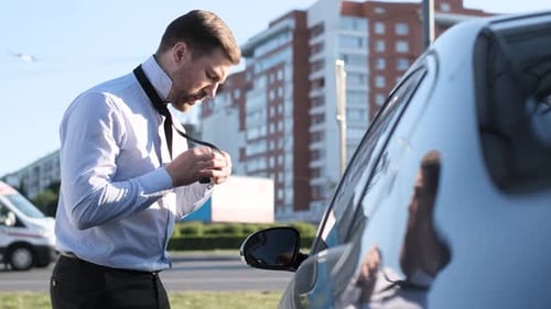 Man Adjusting Tie Beside Car in City