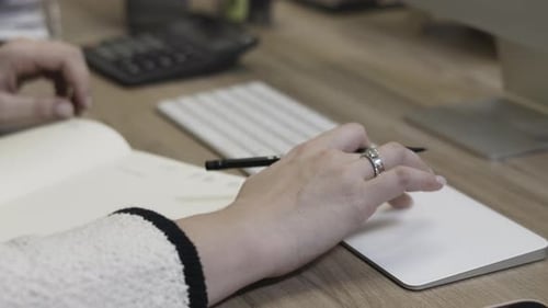 Closeup of Hands at a Desk Working on a Computer and Taking Notes in an Office Setting